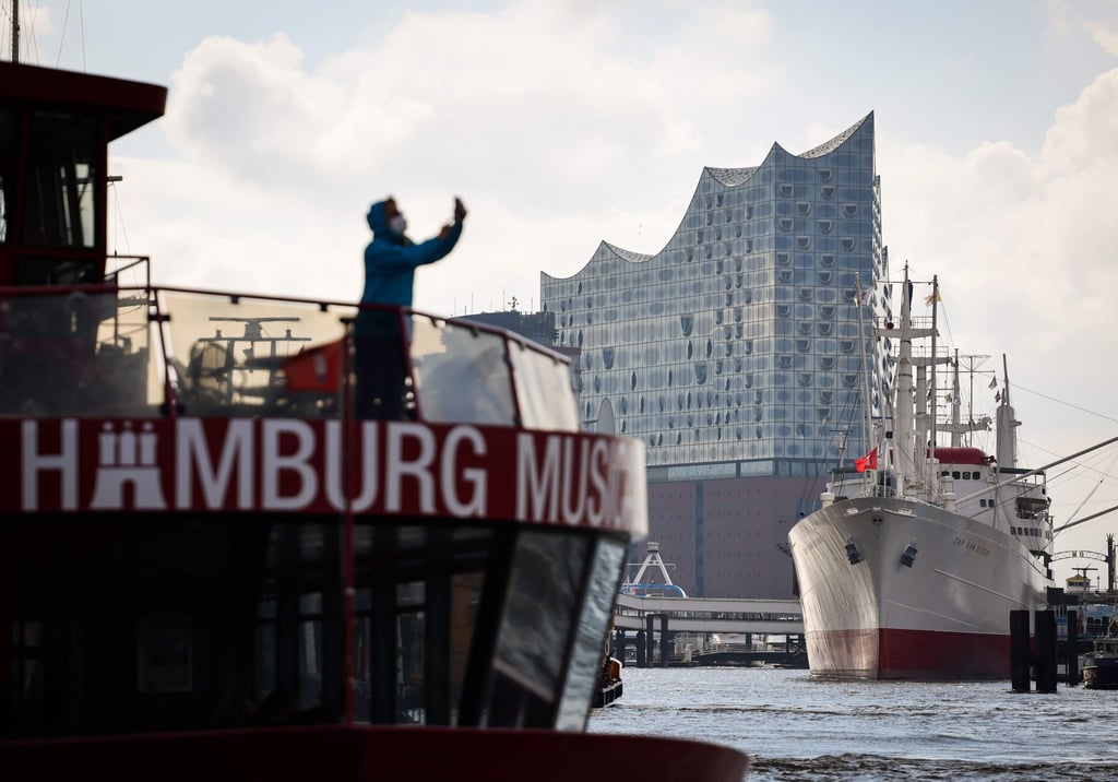 Vor der Elbphilharmonie und dem Museumsschiff Cap San Diego macht eine Frau ein Bild.