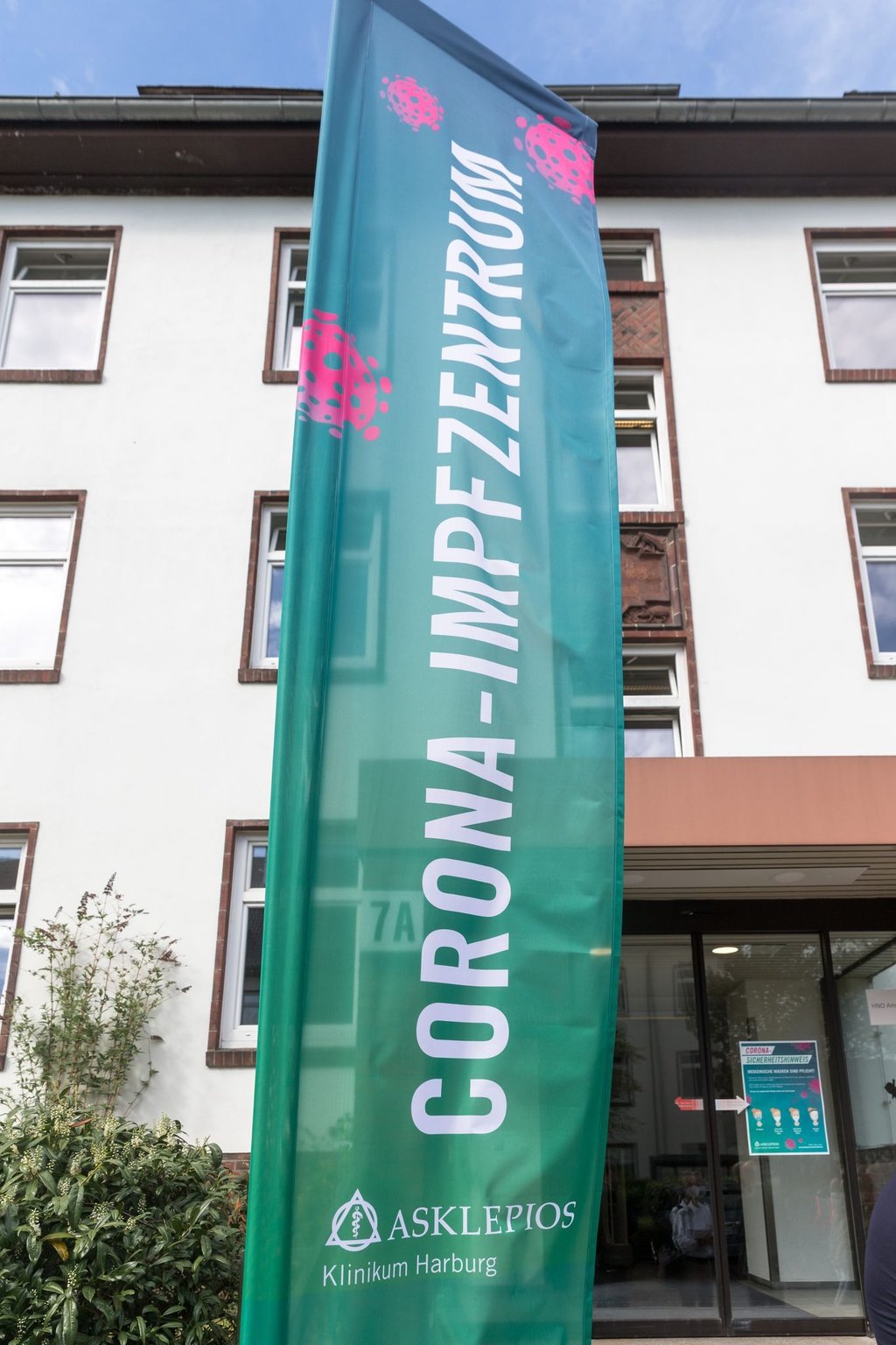 Ein Fahne mit der Aufschrift "Corona-Impfzentrum" weht vor dem Eingang von Haus 7 des Krankenhauses Harburg.
