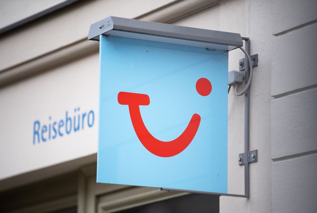 Das Logo des Reiseunternehmens TUI hängt neben einem Reisebüro.