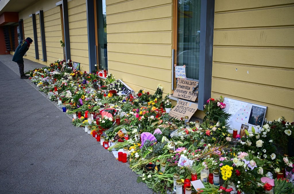 Eine Frau betrachtet vor dem Oberlinhaus die Blumen und Beileidsbekundungen.
