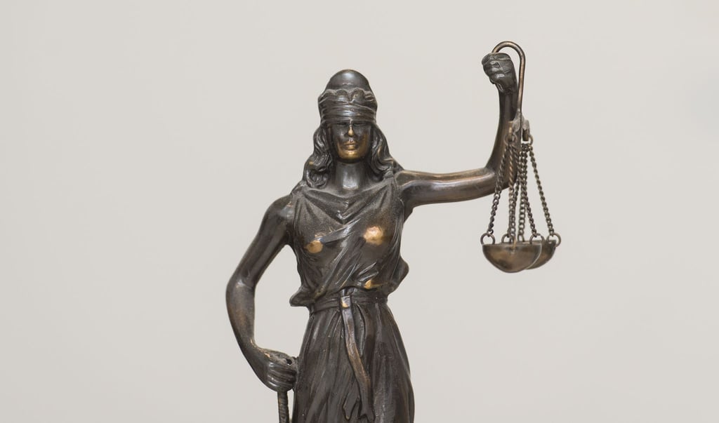 Eine Figur „Justitia“ steht auf einem Schreibtisch.