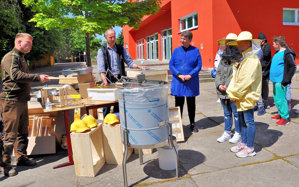 Der Imker Mathias Schultz (l.) erklärte den Schülern und Ministerin Claudia Dalbert sowie Wolfgang Zahn von der Agrarmarketing-Gesellschaft des Landes, welche Arbeitsgänge notwendig sind, um den Honig gewinnen zu können.