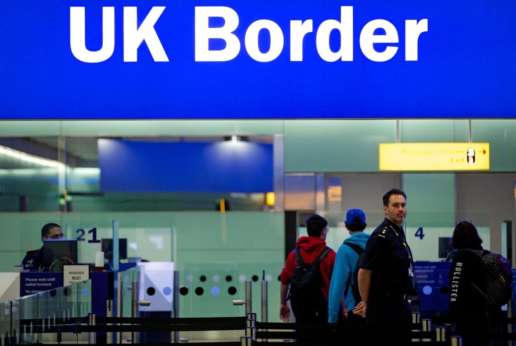 Grenzbeamte stehen am Flughafen Heathrow in London unter einem Schild mit der Aufschrift „UK Border“.