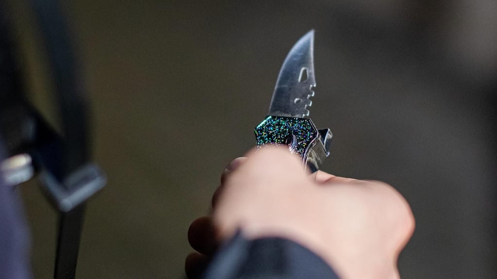 Ein Polizist hält ein sichergestelltes Messer in der Hand.