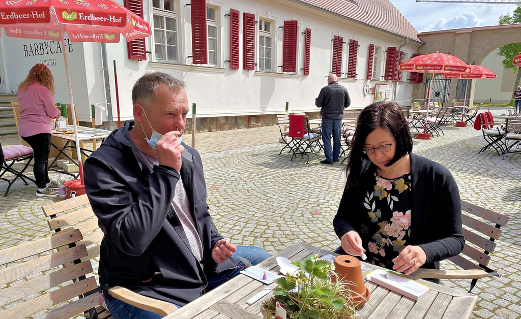 Gäste machen vor dem Besuch einer Gaststätte in Loburg einen Corona-Schnelltest.