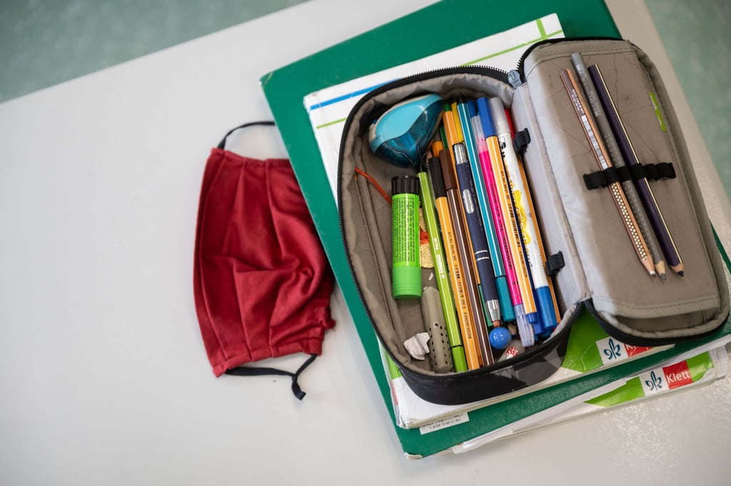 Eine Atemschutzmaske liegt neben einem Federmäppchen.