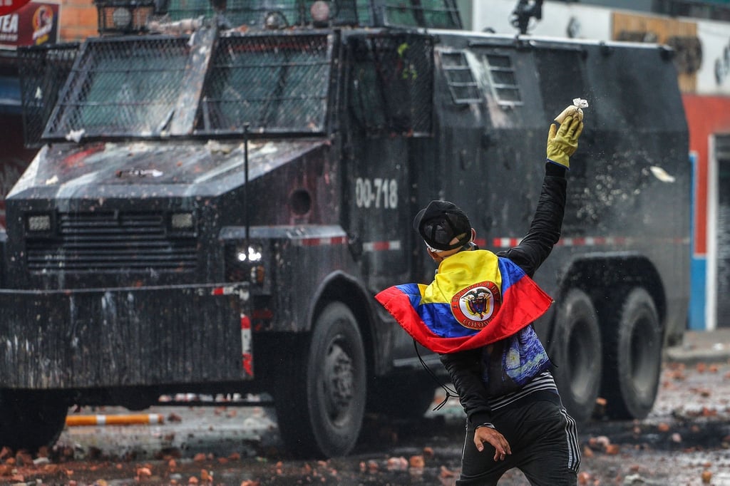Ein Protestler wirft in einem Außenbezirk von Bogotá einen Farbbeutel auf ein Polizeifahrzeug.