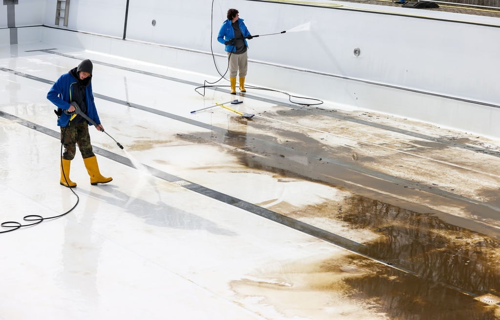 Mitarbeiter der Bäder Halle GmbH reinigen das große Becken im Nordbad.