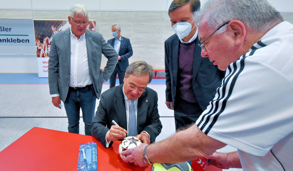 Kanzlerkandidat Armin Laschet unterschreibt auf einem Handball des SV Friesen Frankleben. Vereinschef Jürgen Pohle (r.), Ortsbürgermeister Günter Küster (l.) und Braunsbedras Stadtratsvorsitzenden Sven Czekalla freut?s.