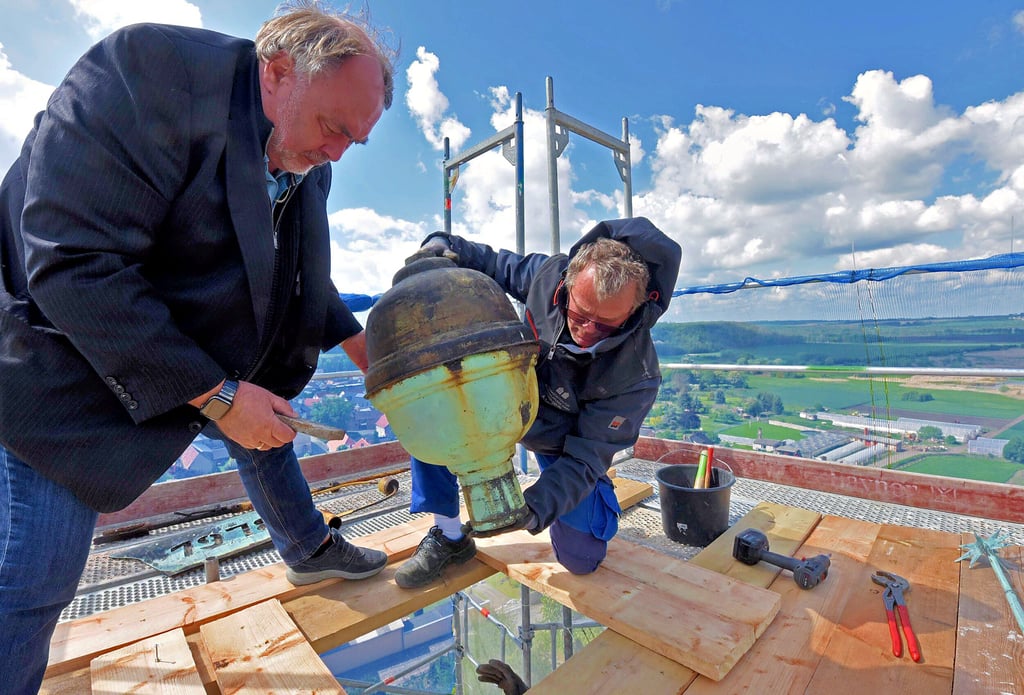 Weit oben: Rüdiger Kempe (links), der Vorsitzende des Gemeindekirchenrates, hilft dabei, den historischen Turmknopf von der Spitze der Froser Stiftskirche abzubauen. Die Halterung war schon völlig verrostet.