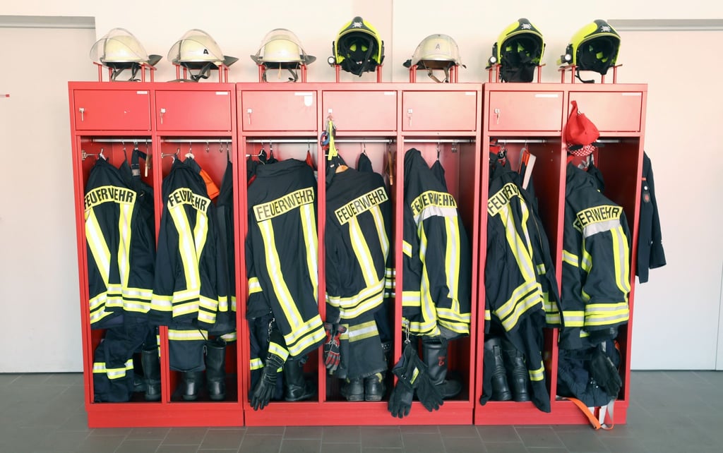 Feuerwehrjacken und -helme hängen in einem Schrank.