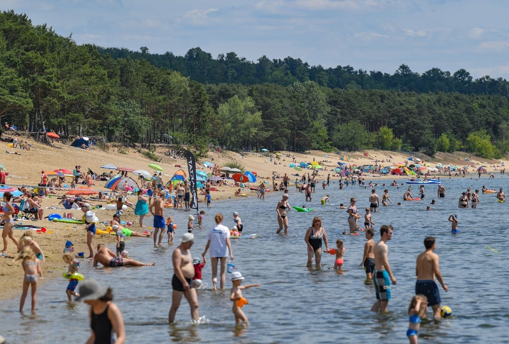 Badegäste sind am Strand und im Wasser des Helenesees zu sehen.