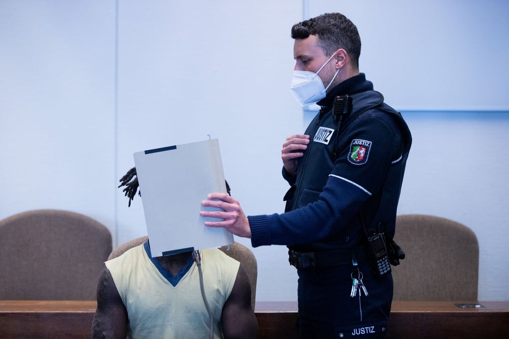 Der Angeklagte wird in Handschellen in einen Gerichtssaal im Landgericht Köln geführt.