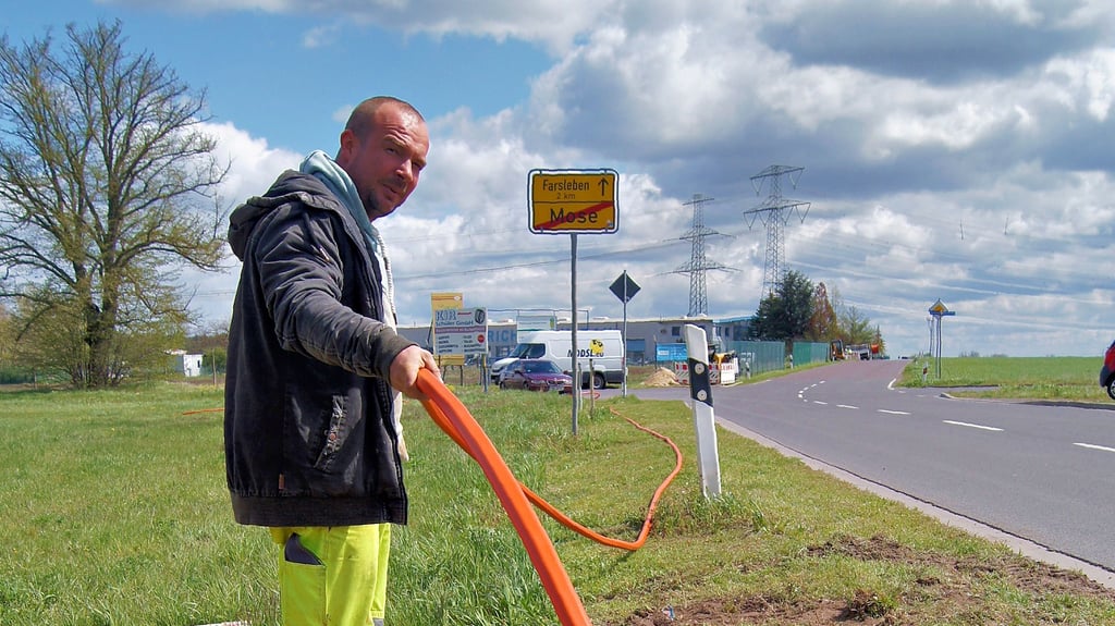 MDDSL-Mitarbeiter Arne Katzwinkel achtet darauf, dass das Leerrohr an der richtigen Stelle in den Boden gezogen wird. Beim Bohrspülverfahren werden nur punktuell Löcher gebaggert.