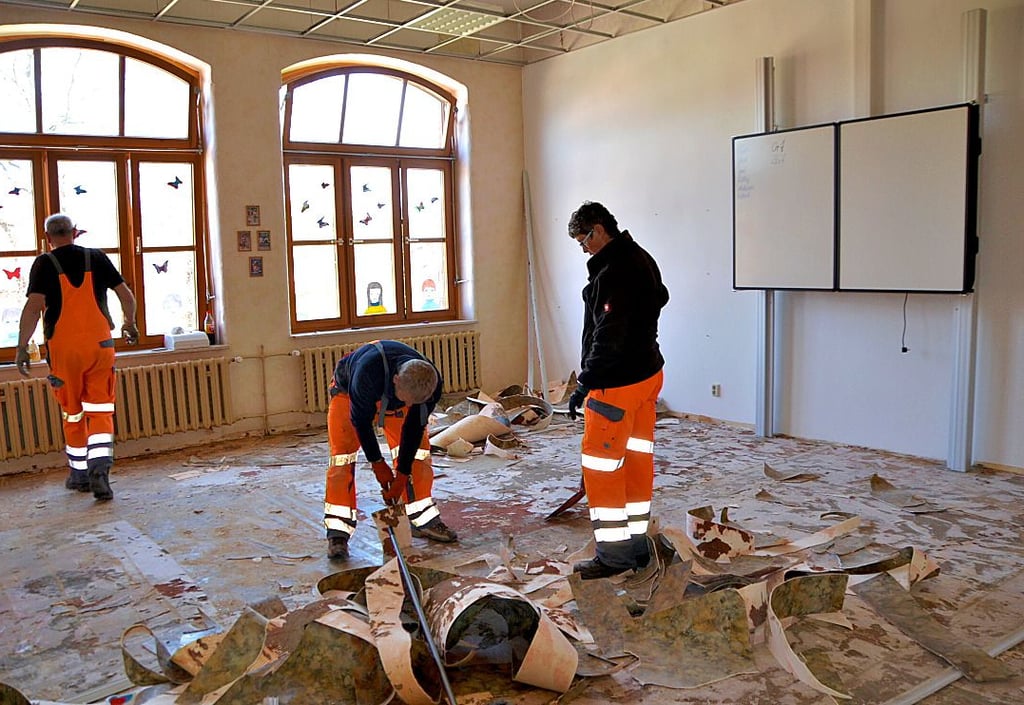 Die Mitarbeiter des Bauhofes, Dieter Herzberg und Irina Weiher (von links) entfernen den Fußboden in einem Klassenzimmer in der Hamersleber Grundschule.