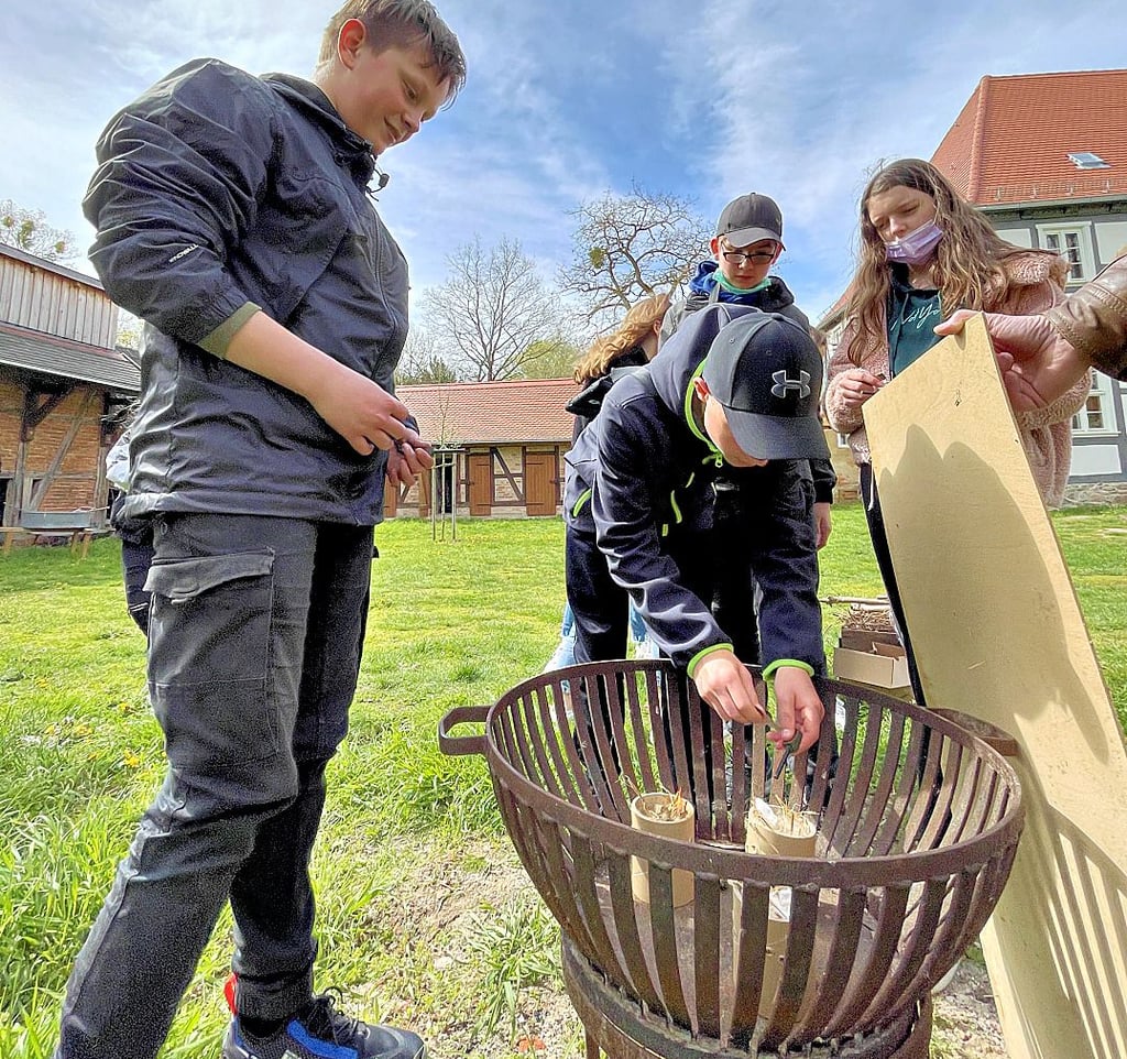 Sekundarschüler versuchen, mit Feuerstein auf dem Pfarrhof Feuer zu machen.