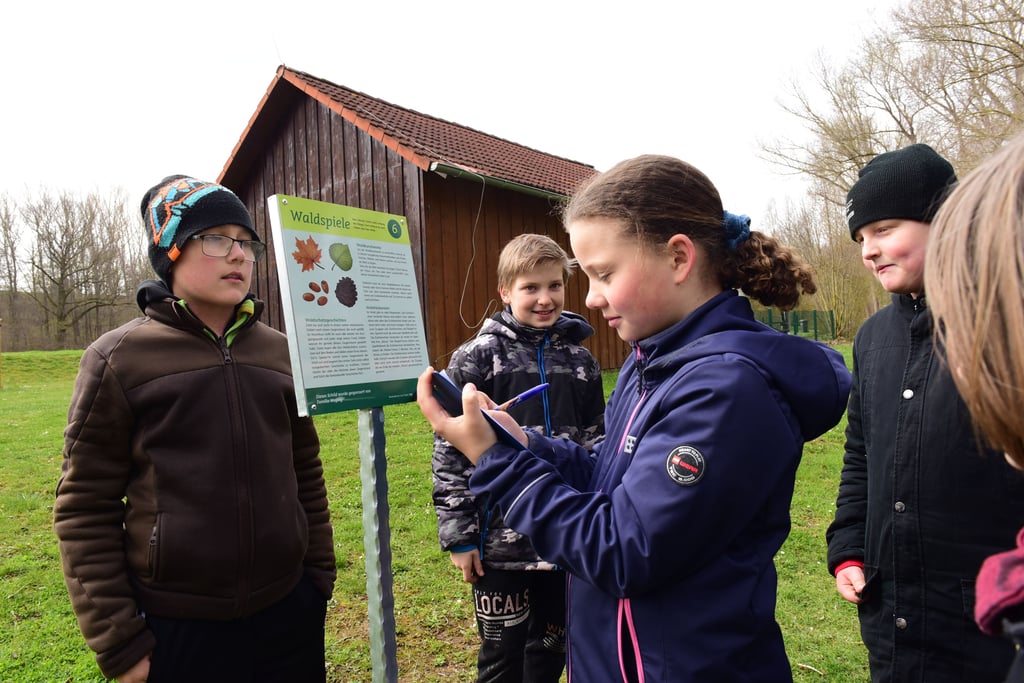 Schülerin Luisa von der Naturgrundschule Heiligenthal macht sich am Erlebnispfad „Der Schatz des Waldes“ Notizen zu den Stationen.