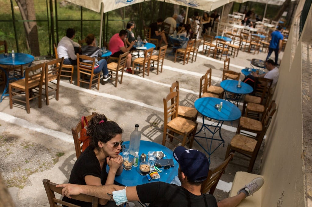 Gäste sitzen in einem Café im Stadtteil Monastiraki im Zentrum Athens.