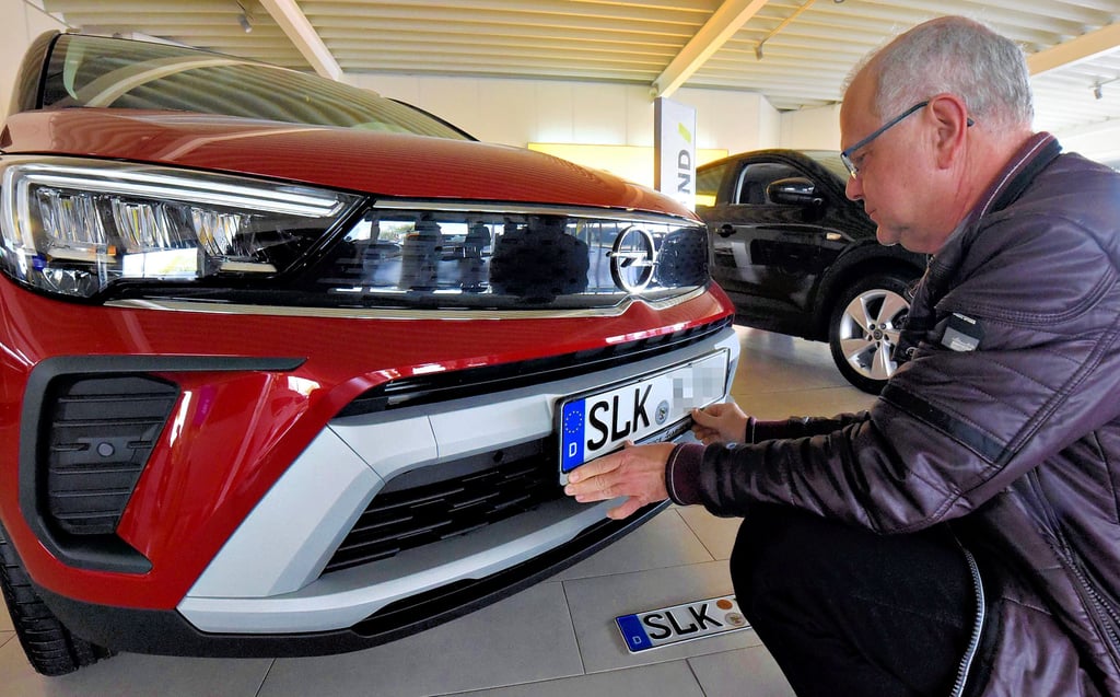 Zulassung geglückt: Opel-Mitarbeiter Matthias Suchomel bringt die neuen Kennzeichentafeln an.