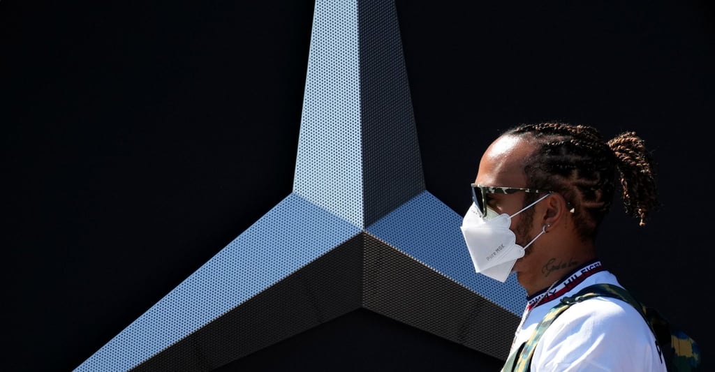 Der Brite Lewis Hamilton vom Team Mercedes geht im Fahrerlager an der Rennstrecke an einem Mercedes-Logo vorbei.