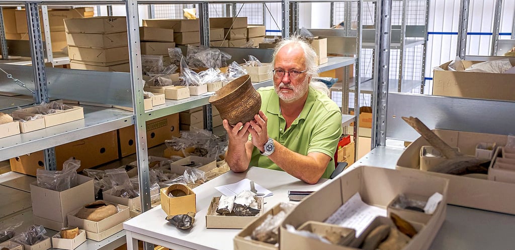 Der Archäologe Prof. Dr. François Bertemes sitzt im Depot des Instituts für Kunstgeschichte und Arachäologien Europas. Vor sich hat er alte Funde. (2019)