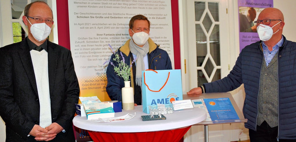 Andreas Becker, Lehrer am Gymnasium Martineum, Halberstadts Oberbürgermeister Daniel Szarata und Klaus Begall, Ärztlicher Direktor des Ameos-Klinikums Halberstadt, bei der Übergabe der Impfstoff-Ampullen und einer Halterungspalette für die kleinen Fläschen, die im 3D-Drucker des Martineums für das Impfzentrum Harz hergestellt worden waren.