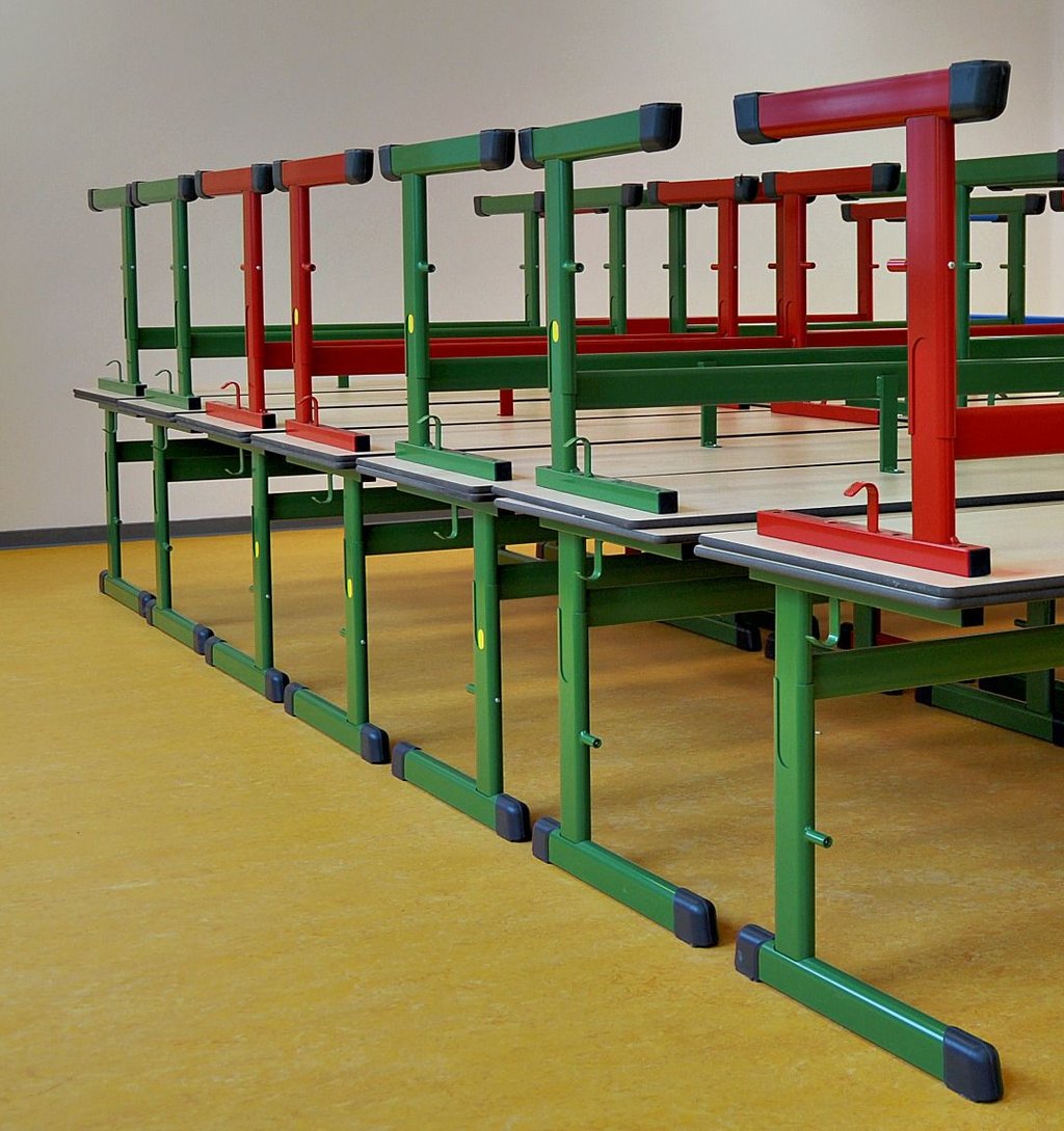 Schultische in bunten Farben warten bereits in den Klassenräumen.