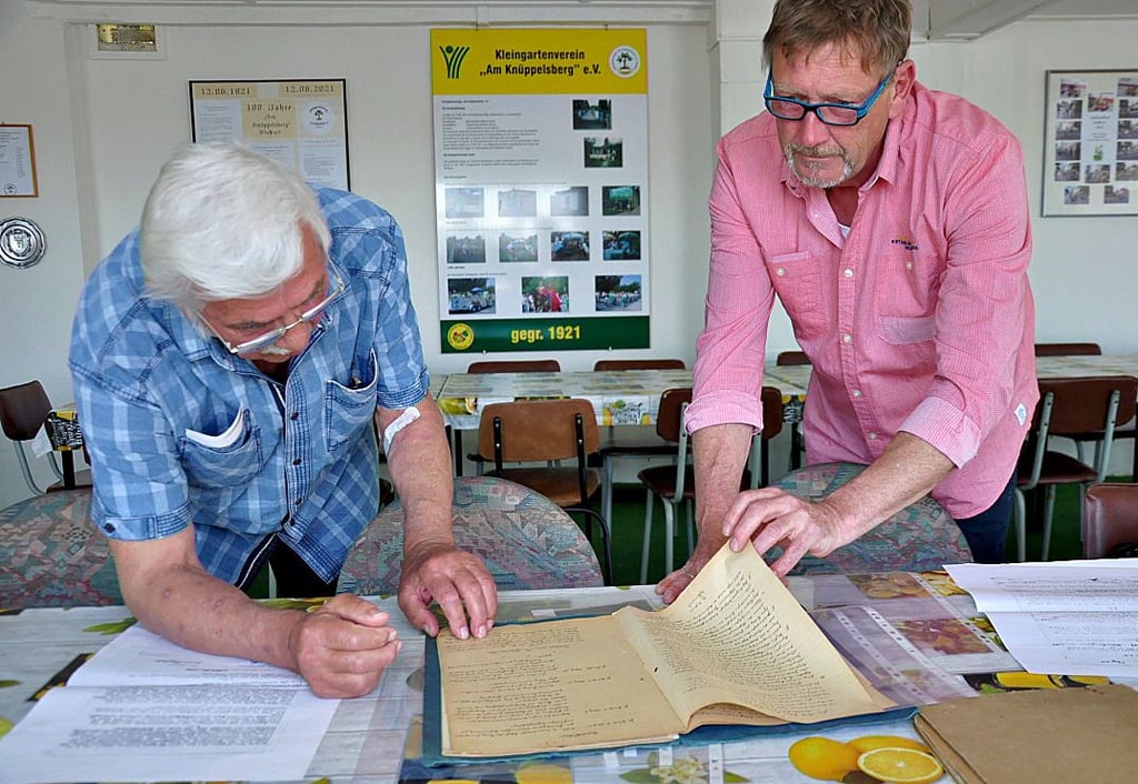 Klaus Boas (links), Pächter in dritter Generation und Vereinsvorsitzender Uwe Radl blättern im Vereinshaus in historischen Unterlagen, unter anderem Pachtverträge von 1922 oder Produktionsberichten von 1952.