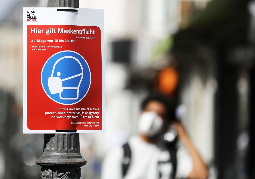 Ein Schild mit der Aufschrift «Hier gilt Maskenpflicht» hängt in einer Fußgängerzone.
