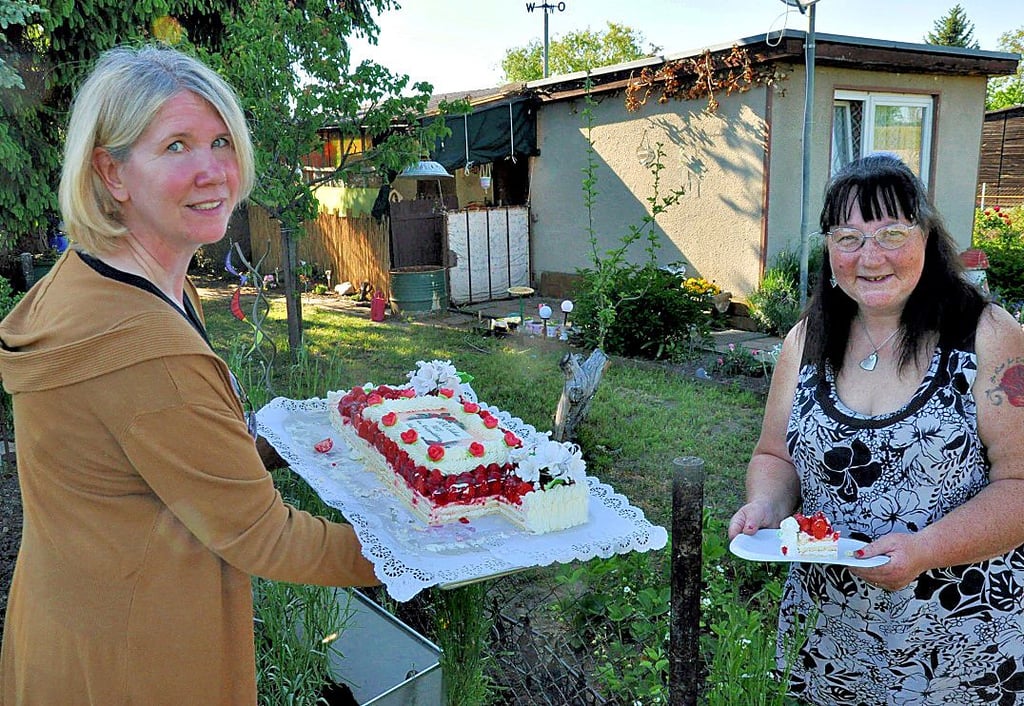 Mit einer Jubiläums-Erdbeertorte überraschte die Finanzerin des Vereins Birgit Radl (links) übern Gartenzaun die Frauen, die sich bei Frühjahrsputz im Vereinshaus ins Zeug legten, wie zum Beispiel Karin Kemper.