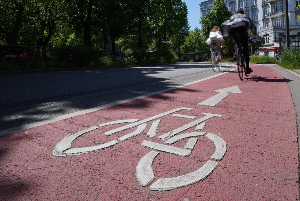 Radfahrer fahren auf der mit roter Farbe markierten Fahrradspur.