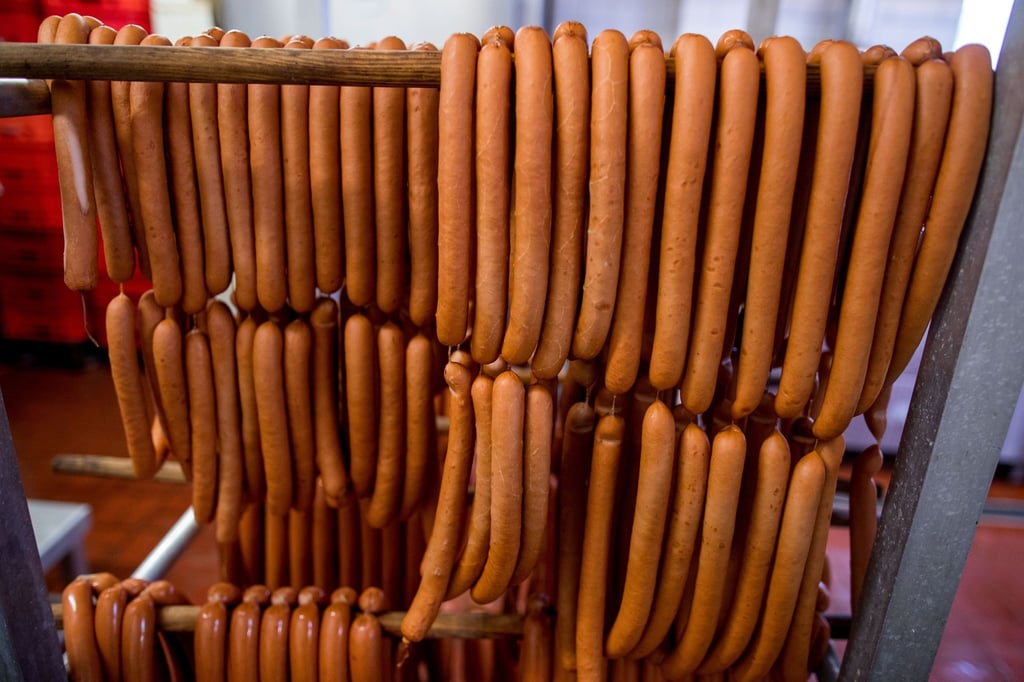 Wiener Würstchen hängen in der Wurstfertigung einer Fleischerei.