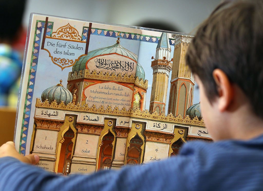 Ein Junge liest während des islamischen Religionsunterrichts in einem Schulbuch.