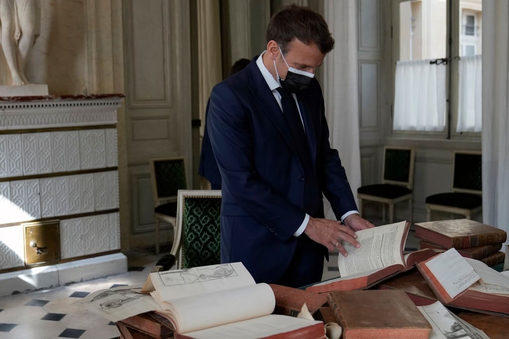 Präsident Emmanuel Macron blättert in alten Büchern.