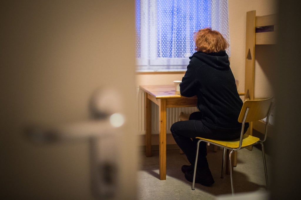 Eine Frau blickt in einem Frauenhaus aus dem Fenster.