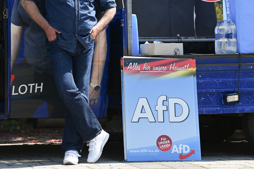 Ein Mann steht vor Beginn einer Wahlkampfveranstaltung der AfD neben einem Wahlpalakt der Partei.