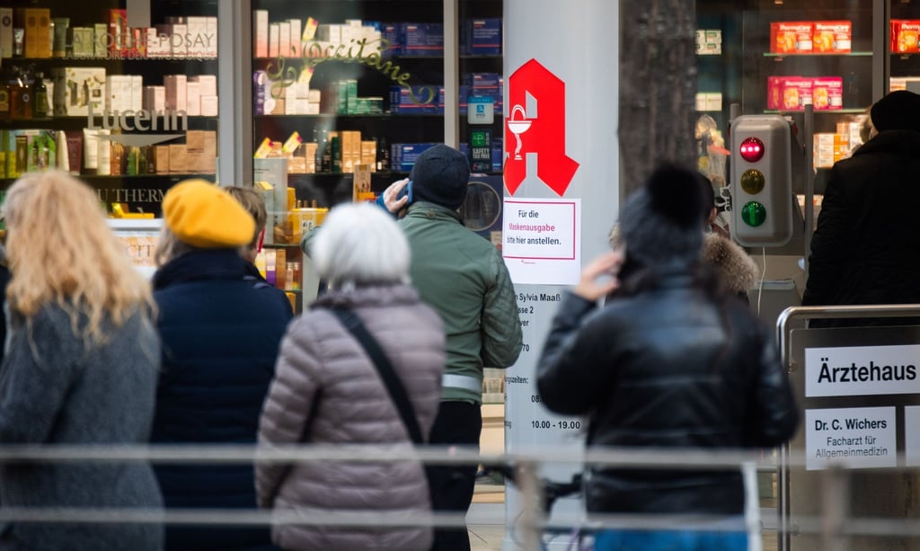 Passanten stehen Schlange vor einer Apotheke.