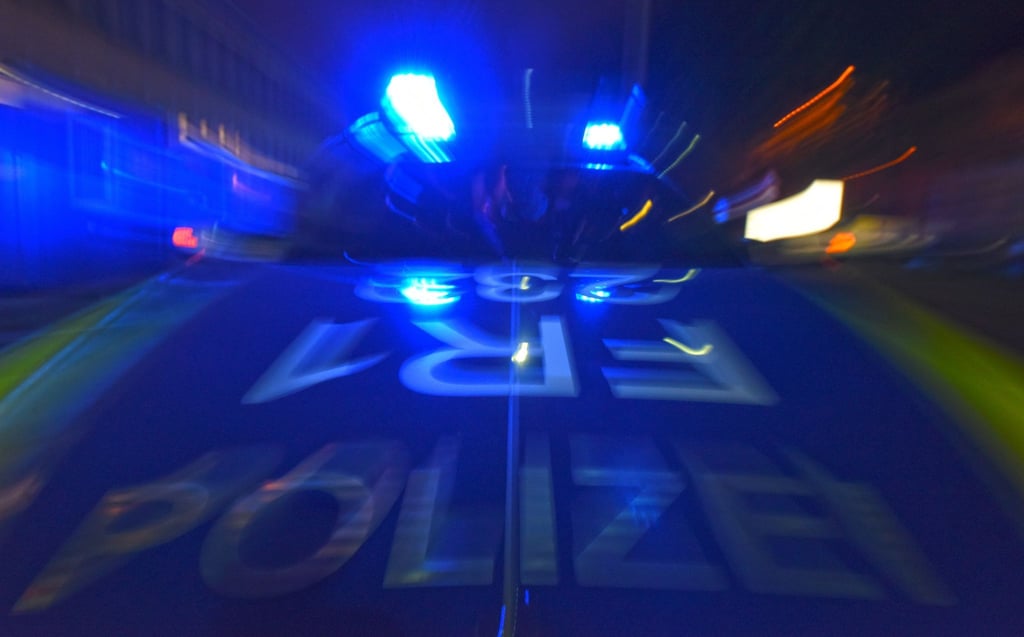 Ein Polizeifahrzeug steht mit Blaulicht auf der Straße.