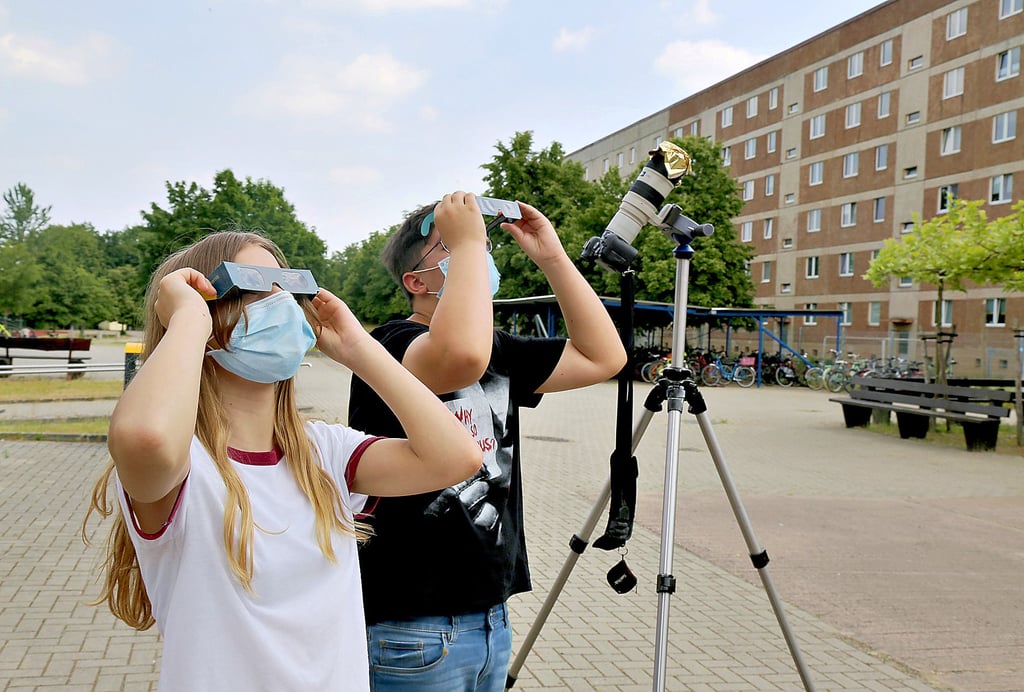 Schüler der Lessing-Gemeinschaftsschule in Salzwedel, wie hier Marie Kahlert und Paul Lennox Lemke (v. links) aus der Klasse 7b, haben mit Spezialbrillen die Sonnenfinsternis von ihrem Schulhof aus beobachtet.