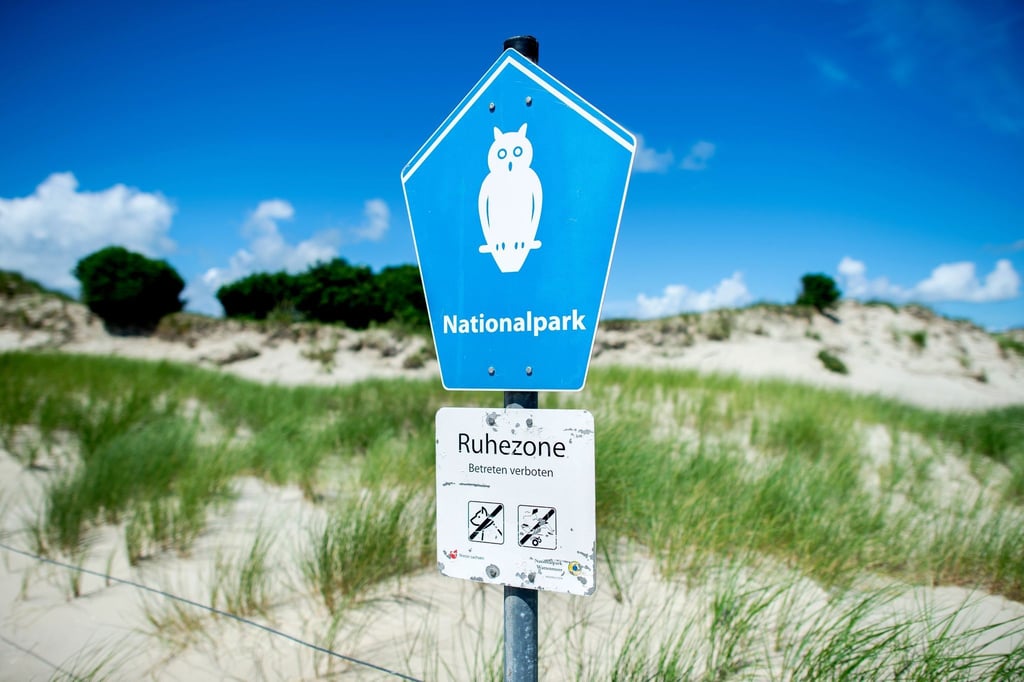 Ein Schild mit der Aufschrift „Nationalpark“ steht vor der Dünenlandschaft am Ostende der Insel Norderney.