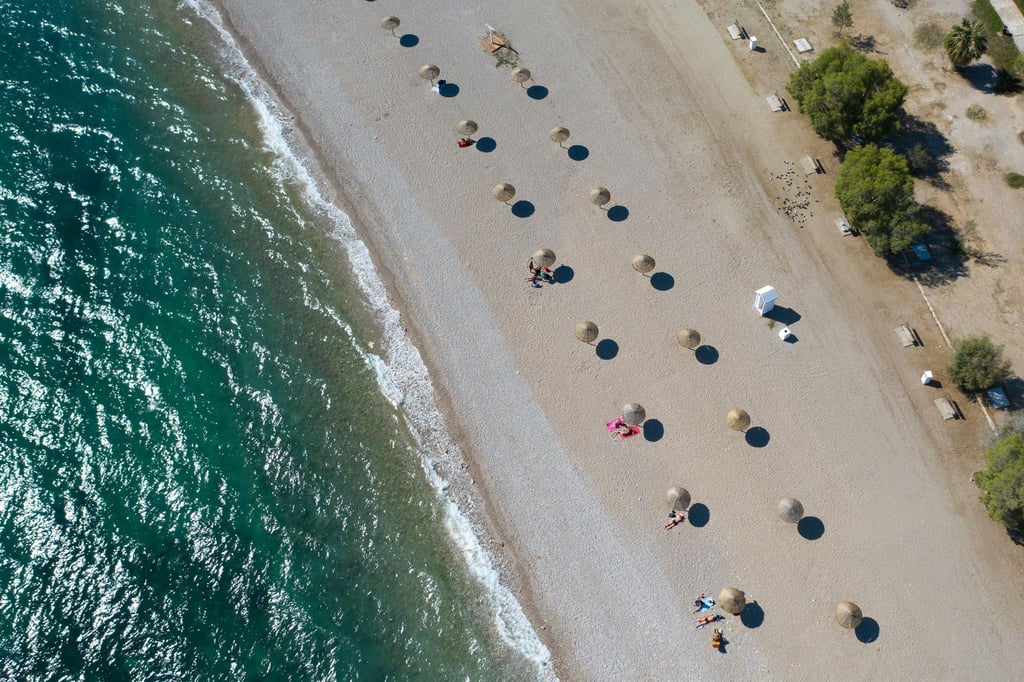 An einem Strand südlich von Athen stehen Sonnenschirme für Strandbesucher bereit.