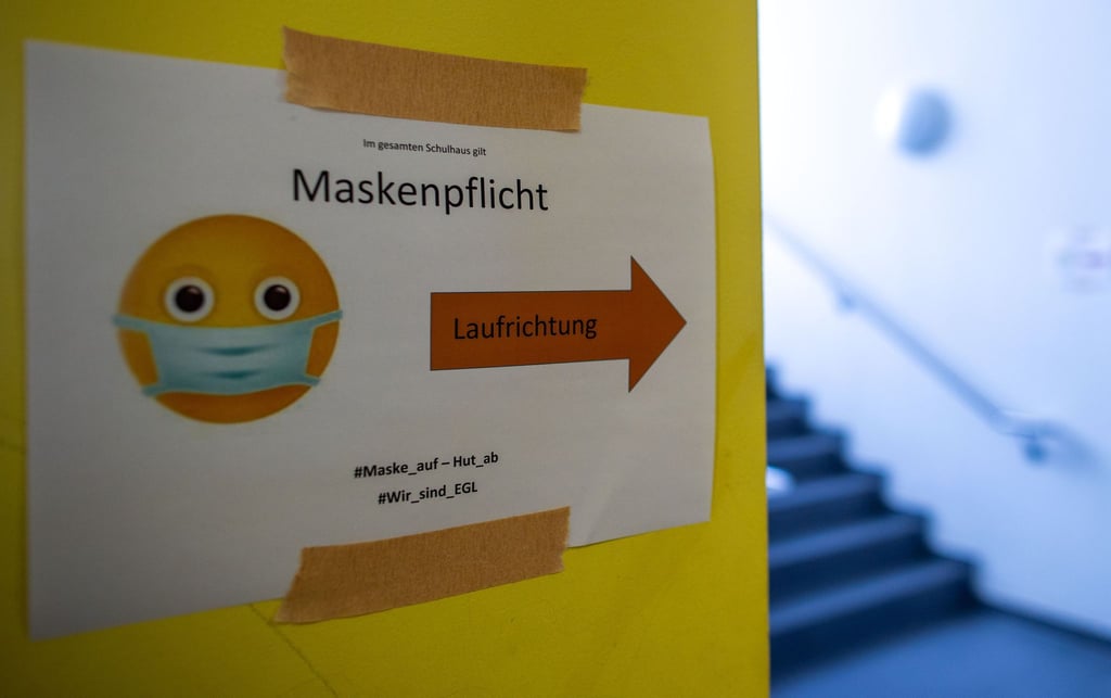 Ein Schild weist in einer Schule auf die Maskenpflicht hin.