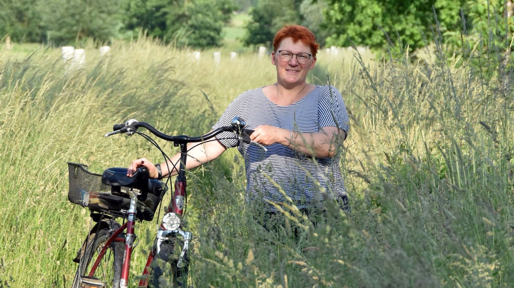 Janett Segler führt vor, dass das Fahrradfahren auf dem verwilderten Weg an der Landesstraße 24 von Rätzlingen nach Kathendorf wegen des hohen Grases nicht möglich ist.