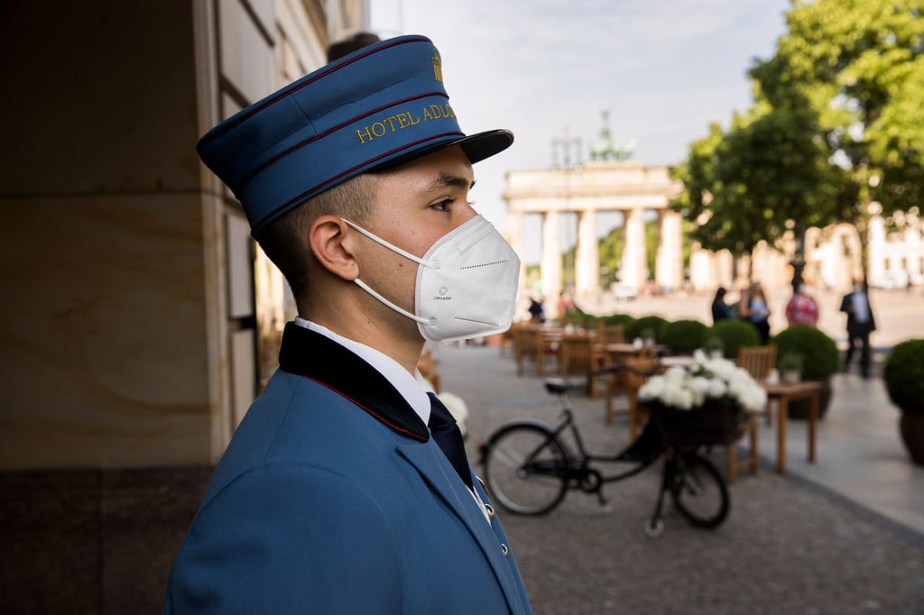 Ein Page steht vor dem Hoteleingang des Hotel Adlon Kempinski am Pariser Platz.