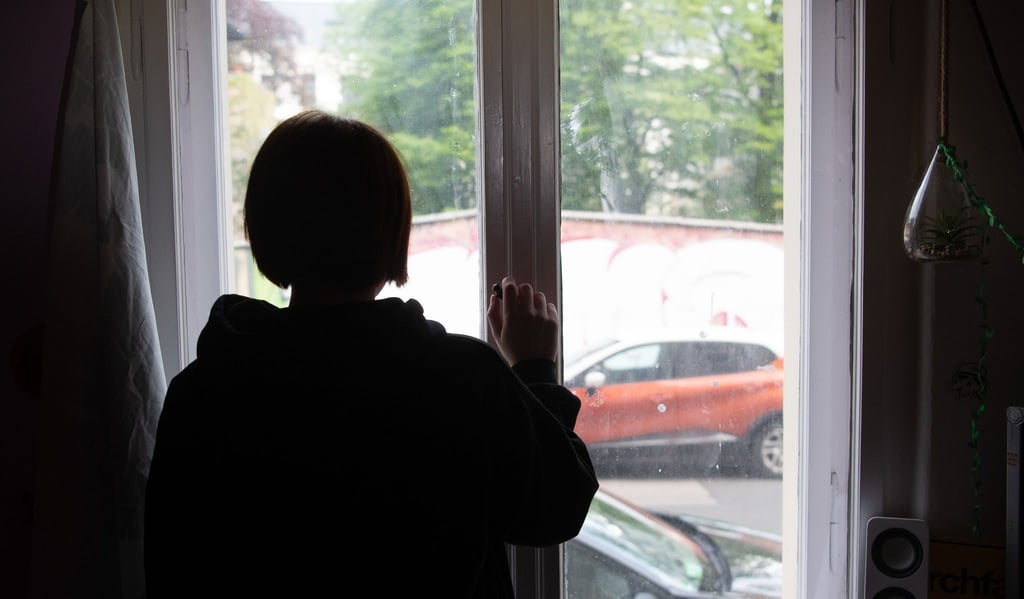 Eine Jugendliche blickt aus einem Fenster.