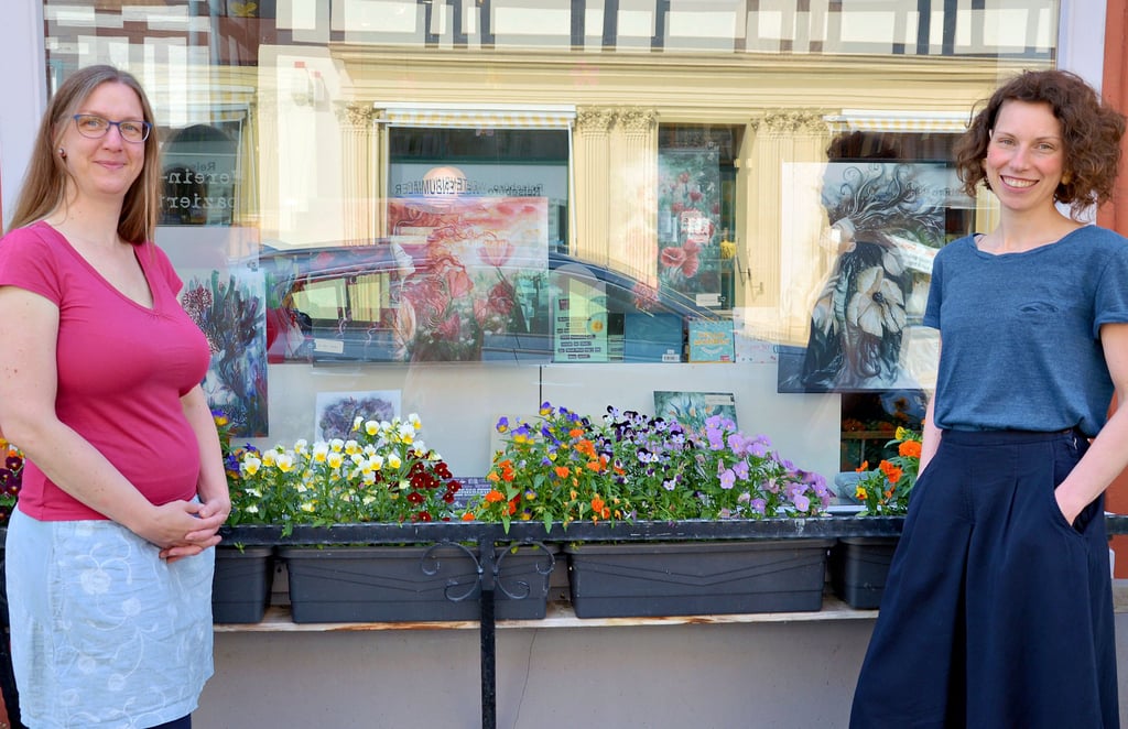 Susann Schmundt (links) und Hobbymalerin Maria Hermann vor dem Schaufenster der Rathausbuchhandlung in Tangermünde, in dem die Bilder zu sehen sind.