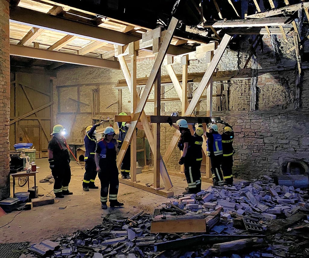Die THW-Fachleute aus Quedlinburg sichern die Tordurchfahrt an der halb eingestürzten Toreinfahrt durch eine Holzstützkonstruktion.