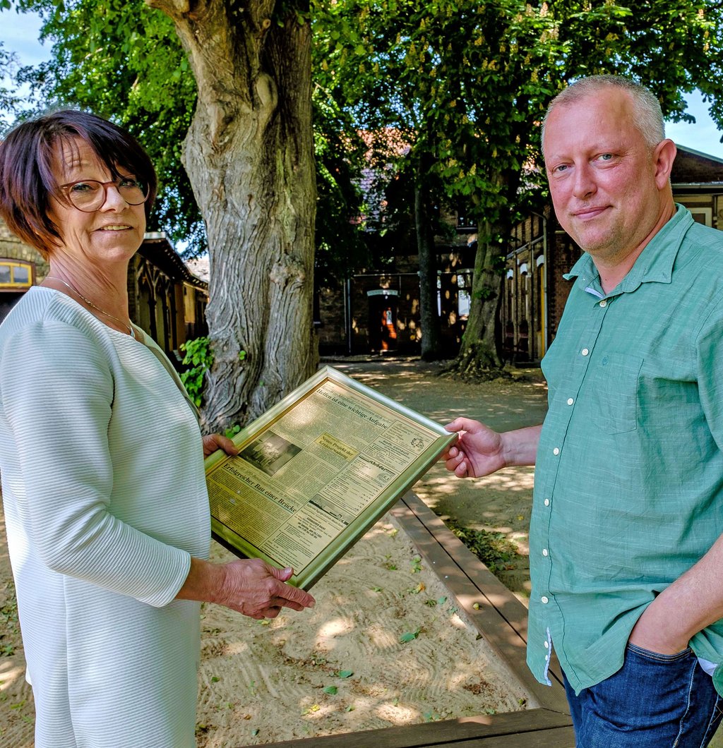 Cornelia Freygang und Tobias Baumgarte, beide im Vorstand von Reso-Witt, mit einer gerahmten MZ-Seite, in der es um die Gründung des Vereins im Juni des Jahres 1991 geht.