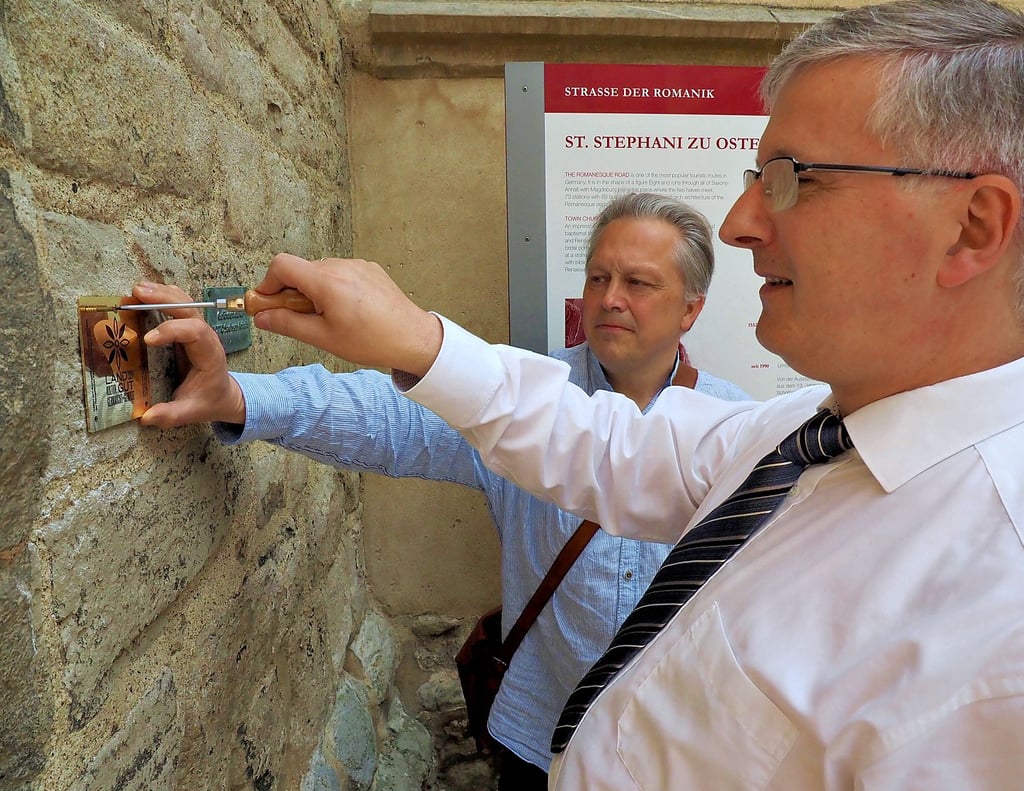 Die erste der vier Schrauben der Projektplakette drehte Pfarrer Sebastian Beutel, assistiert von Klaus-Martin Bresgott, ins Mauerwerk des Kirchturms.
