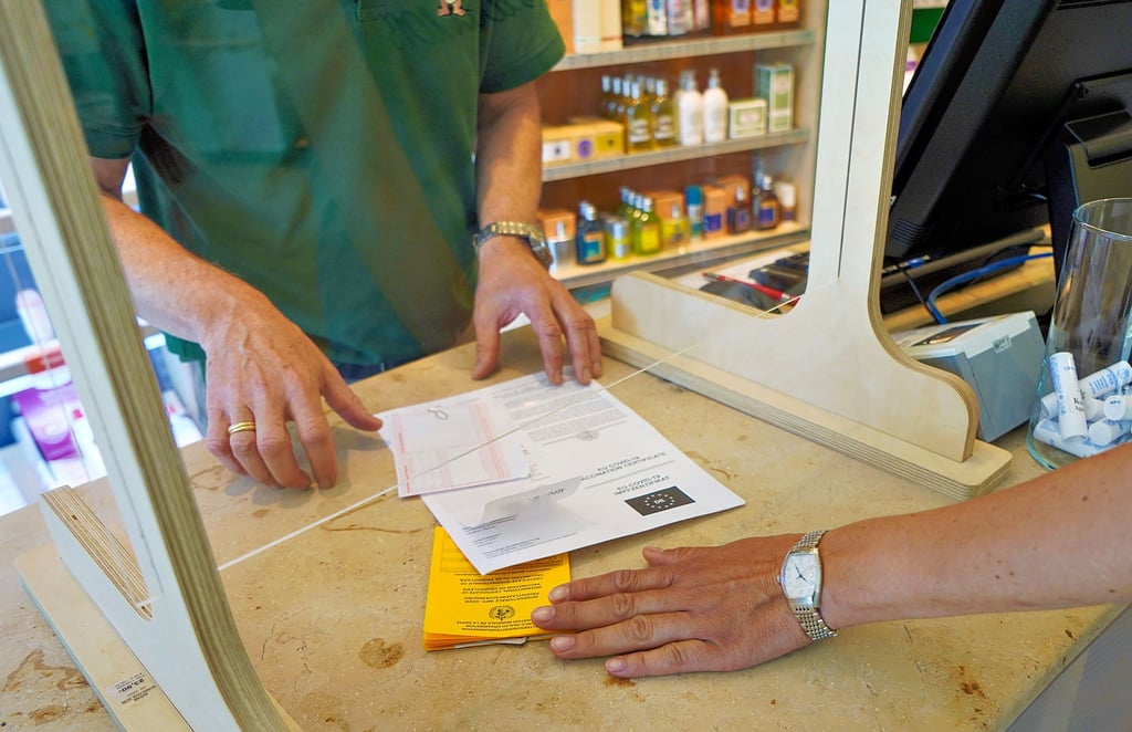 Eine Kundin übergibt ihren Impfpass und ein Covid-19 Impfzertifikat in einer Apotheke, um sich einen digitalen Impfnachweis ausstellen zu lassen. Nach anfänglichen Problemen am Montagmorgen klappt das in Staßfurt schon gut.